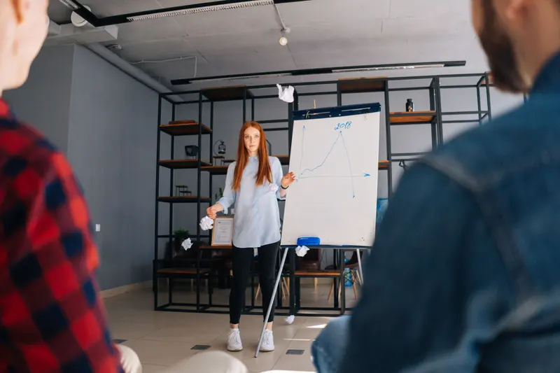 Frau präsentiert vor Publikum am Flipchart