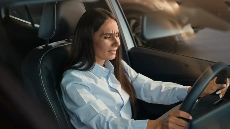 Frau sitzt angespannt am Steuer im Auto